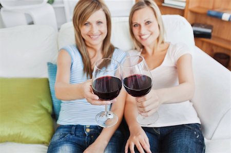 Two cute women holding a wineglass on a sofa at home Stock Photo - Budget Royalty-Free & Subscription, Code: 400-04716464