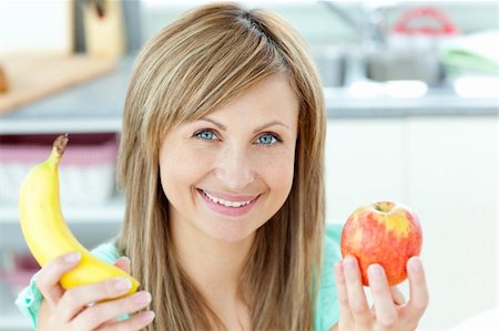 pretty women eating banana - Positive caucasian woman holing a banana and an apple in the kitchen at home Stock Photo - Budget Royalty-Free & Subscription, Code: 400-04716516