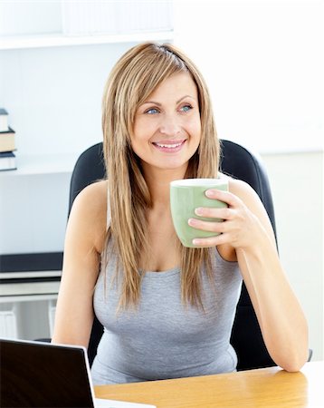 simsearch:400-05749531,k - Glowing businesswoman holding a cup using her laptop at her desk Stock Photo - Budget Royalty-Free & Subscription, Code: 400-04716665