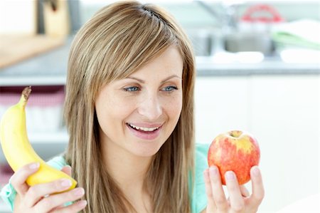 pretty women eating banana - Jolly young woman holding an appke and a banana sitting in the kitchen Stock Photo - Budget Royalty-Free & Subscription, Code: 400-04716690