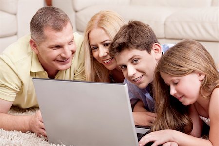 simsearch:400-04044108,k - Happy family of four browsing on laptop as they relax on carpet in living room Stock Photo - Budget Royalty-Free & Subscription, Code: 400-04710195