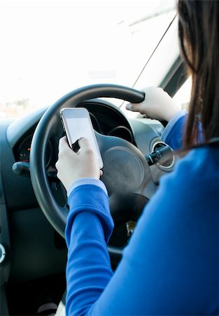 Young brunette woman using her cellphone while driving in her car Stock Photo - Budget Royalty-Free & Subscription, Code: 400-04710287