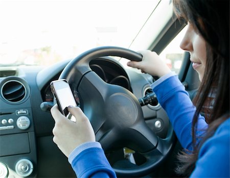Beautiful brunette woman using her cellphone while driving in her car Stock Photo - Budget Royalty-Free & Subscription, Code: 400-04710288