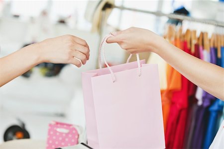 A saleswoman giving a shopping bag to a customer in a clothes store Stock Photo - Budget Royalty-Free & Subscription, Code: 400-04711405