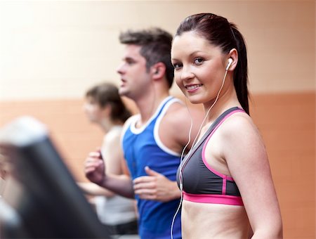 simsearch:400-05677914,k - Young beautiful athletes with earphones exercising on a running machine in a fitness center Stock Photo - Budget Royalty-Free & Subscription, Code: 400-04724128