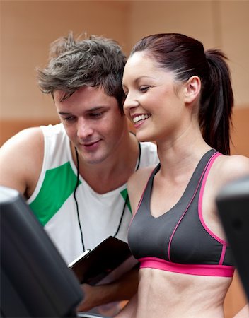 simsearch:400-04256139,k - Cheerful athletic woman standing on a running machine with her personal coach in a fitness center Stock Photo - Budget Royalty-Free & Subscription, Code: 400-04724131