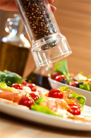 A peppermill grinding pepper onto a seafood salad of smoked salmon and shrimp or prawns, shot in golden light with olive oil and balsamic vinegar out of focus in the background. Stock Photo - Budget Royalty-Free & Subscription, Code: 400-04726706