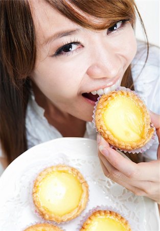 Close up young woman enjoying egg tart Foto de stock - Super Valor sin royalties y Suscripción, Código: 400-04727022