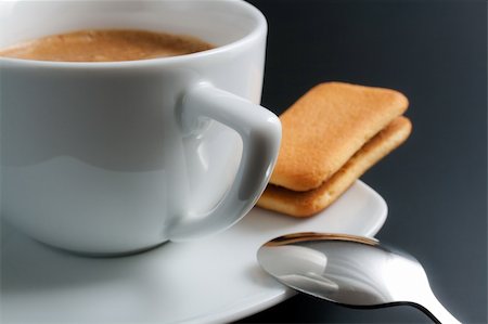 White porcelain cup of freshly brewed coffee close-up arranged with sandwich-biscuit spoon and plate on dark background Stock Photo - Budget Royalty-Free & Subscription, Code: 400-04728162