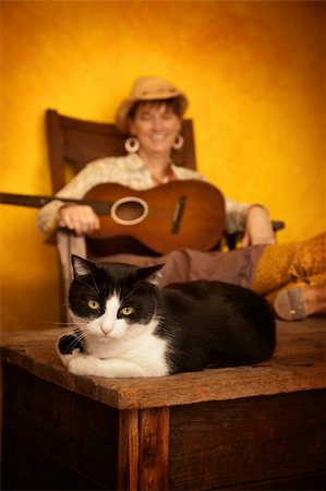 Pretty western woman in antique rocking chair with guitar and cat Stock Photo - Budget Royalty-Free & Subscription, Code: 400-04729408