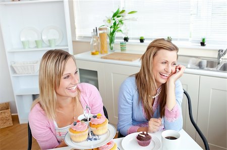simsearch:400-04729451,k - Two cheerful female friends eating pastries and drinking coffee in the kitchen at home Stock Photo - Budget Royalty-Free & Subscription, Code: 400-04729451