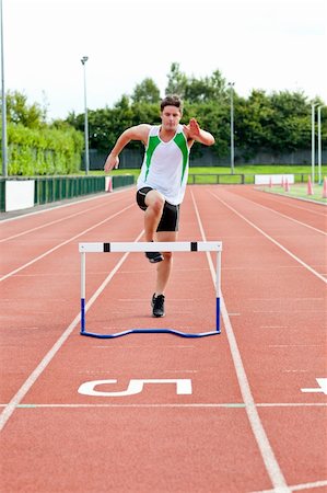 Sporty man jumping above hedge during a race in a stadium Stock Photo - Budget Royalty-Free & Subscription, Code: 400-04729507