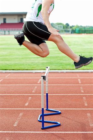 Determined male athlete jumping above hedge during a race in a stadium Stock Photo - Budget Royalty-Free & Subscription, Code: 400-04729508