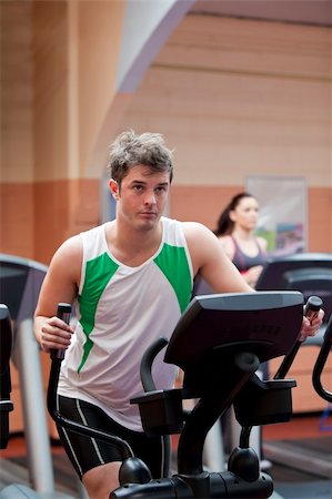 Handsome man doing exercises using a cross trainer in a fitness centre Stock Photo - Budget Royalty-Free & Subscription, Code: 400-04735437