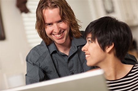 simsearch:400-04349663,k - Pretty Smiling Multiethnic Woman and Caucasian Man Using A Laptop Computer Together. Stock Photo - Budget Royalty-Free & Subscription, Code: 400-04739419