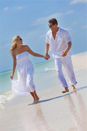 simsearch:400-04082089,k - Happy young man and woman couple running, laughing and holding hands on a deserted tropical beach with bright clear blue sky Stock Photo - Budget Royalty-Free & Subscription, Code: 400-04741121