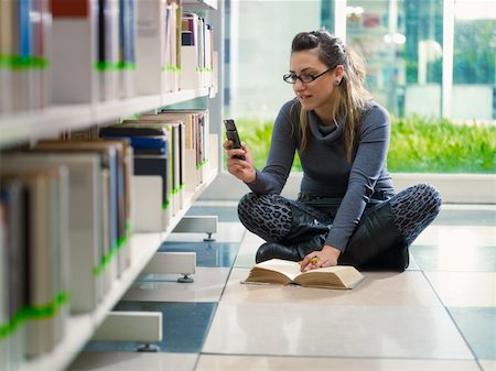 female college student sitting on floor in library, typing on mobile phone. Horizontal shape, front view, full length, copy space Stock Photo - Budget Royalty-Free & Subscription, Code: 400-04743409