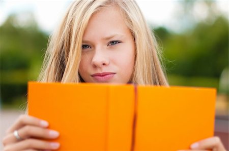 beautiful young student girl, with opened orange book in front of her, looking into the camera Fotografie stock - Microstock e Abbonamento, Codice: 400-04743968
