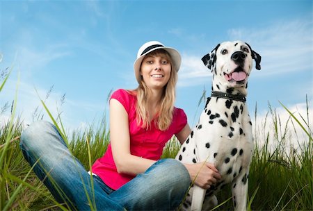 female dalmatian - beautiful young woman in hat sitting in grass with her dalmatian dog pet and smiling. Both looking into the camera. Blue sky in background and green grass in foreground. Stock Photo - Budget Royalty-Free & Subscription, Code: 400-04743989