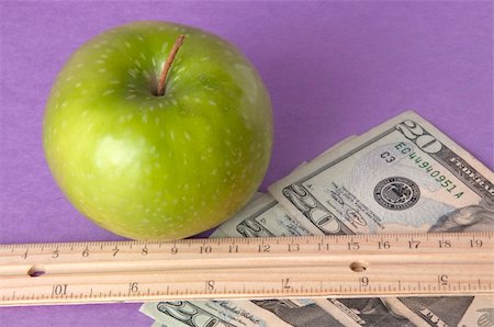 simsearch:400-04758612,k - Conceptual image of a bright green apple with a ruler, and American currency on a vibtrant purple background to represent the cost of education. Stock Photo - Budget Royalty-Free & Subscription, Code: 400-04758616