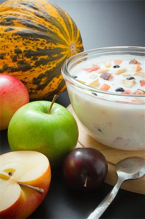 Glass bowl filled with yogurt mixed with fruit pieces arranged with spoon and some fruits around Stock Photo - Budget Royalty-Free & Subscription, Code: 400-04750625
