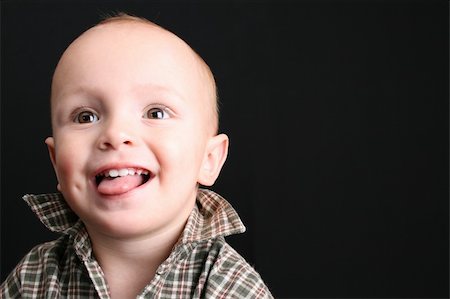 simsearch:400-05727835,k - Blonde toddler against a black background with a big smile Fotografie stock - Microstock e Abbonamento, Codice: 400-04751678