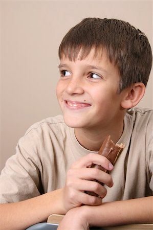 Young boy with big eyes, eating a chocolate bar Photographie de stock - Aubaine LD & Abonnement, Code: 400-04752614