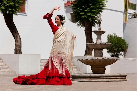 dances of andalucia - Woman traditional Spanish Flamenco dancer dancing in a red dress and cream shawl dancing in a town square with a stone fountain Stock Photo - Budget Royalty-Free & Subscription, Code: 400-04766016