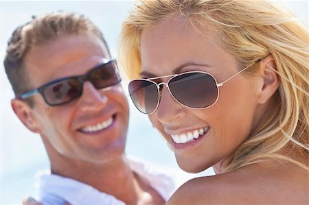 simsearch:400-04082089,k - A happy and attractive man and woman couple wearing sunglasses and smiling in sunshine at the beach Stock Photo - Budget Royalty-Free & Subscription, Code: 400-04766022