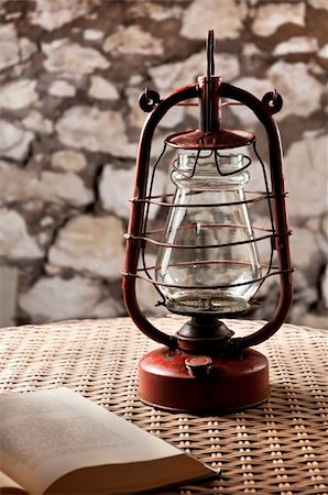 Kerosene lamp stands on a wicker table, next to the book in a dark room Fotografie stock - Microstock e Abbonamento, Codice: 400-04767366