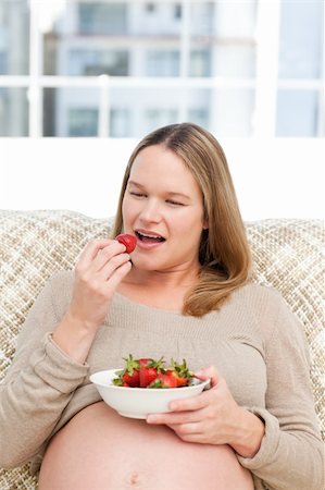 simsearch:400-04767824,k - Hungry pregnant woman eating strawberries sitting in the living-room at home Foto de stock - Royalty-Free Super Valor e Assinatura, Número: 400-04767806