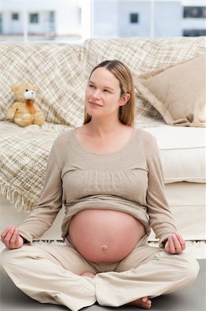 simsearch:400-04767824,k - Pensive pregnant woman doing yoga sitting on the floor of the living room Foto de stock - Royalty-Free Super Valor e Assinatura, Número: 400-04767829