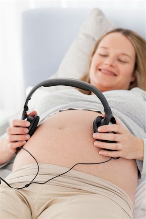 simsearch:400-04266869,k - Happy pregnant woman putting headphones on her belly lying on a bed Stock Photo - Budget Royalty-Free & Subscription, Code: 400-04767860