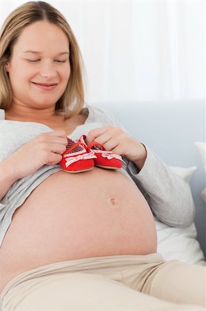 simsearch:400-04266869,k - Cute future mom putting baby shoes on her belly relaxing on a bed Stock Photo - Budget Royalty-Free & Subscription, Code: 400-04769413