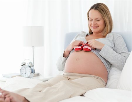 simsearch:400-04767824,k - Cute pregnant woman putting baby shoes on her belly relaxing on a bed Foto de stock - Royalty-Free Super Valor e Assinatura, Número: 400-04769422