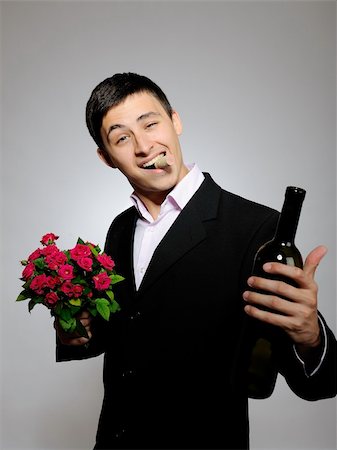 simsearch:400-04655735,k - Handsome romantic young man holding rose flower and vine bottle  prepared for a date. gray background Stockbilder - Microstock & Abonnement, Bildnummer: 400-04760432