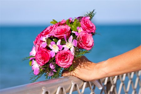 simsearch:400-04161888,k - Close up of a  beautiful vibrant wedding boquet held by the bride in front of a blue ocean Fotografie stock - Microstock e Abbonamento, Codice: 400-04761994