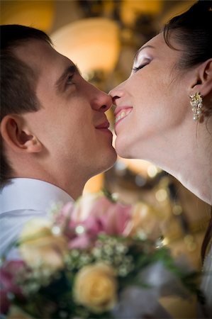 simsearch:400-07332647,k - Beautiful young bride kissing groom in decorated indoor setting Stockbilder - Microstock & Abonnement, Bildnummer: 400-04779465