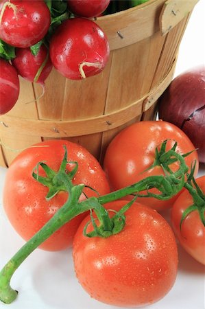 flechtkorb - Still life picture of Tomatoes on the Vine covered with water drops in front of Wooden bushel basket full with radishes over white background. Stockbilder - Microstock & Abonnement, Bildnummer: 400-04772386