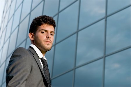 simsearch:400-06091141,k - Young businessman looking to camera on modern building background Photographie de stock - Aubaine LD & Abonnement, Code: 400-04772554