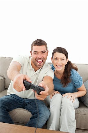 simsearch:400-05297936,k - Happy couple playing video games together sitting on the sofa Stock Photo - Budget Royalty-Free & Subscription, Code: 400-04773002