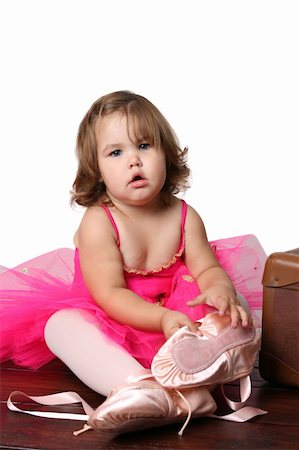 simsearch:400-07302639,k - Little girl wearing a pink ballet outfit sitting next to an antique suitcase trying on oversized ballet shoes Stock Photo - Budget Royalty-Free & Subscription, Code: 400-04773837