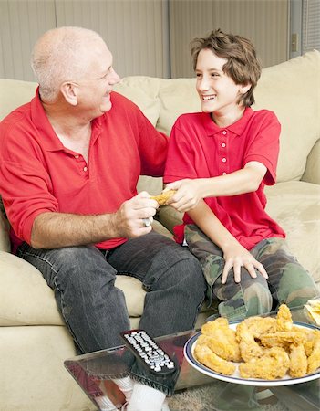 picture of people eating chicken wings - Little boy and his father watching football and fighting over a fried chicken wing. Stock Photo - Budget Royalty-Free & Subscription, Code: 400-04787718