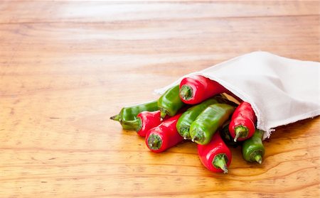 Fresh green and red chilli peppers in a cloth bag, displayed on a beautiful wooden table Stock Photo - Budget Royalty-Free & Subscription, Code: 400-04792282