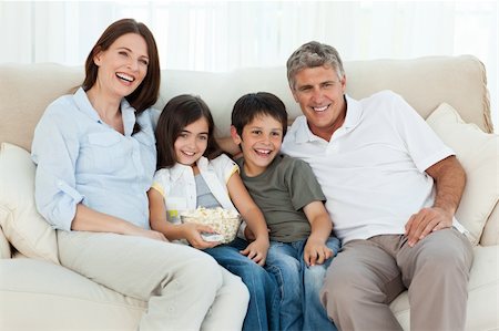 family on sofa popcorn - Family watching tv while they are eating popcorn Stock Photo - Budget Royalty-Free & Subscription, Code: 400-04805345
