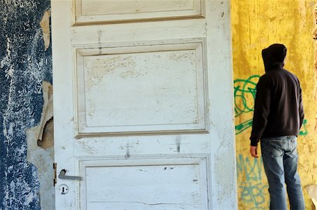 simsearch:400-05352563,k - Hooded figure in abandoned house. Empty room weathered walls torn wallpaper. Fotografie stock - Microstock e Abbonamento, Codice: 400-04805559