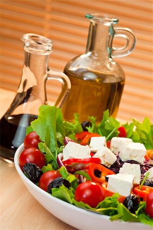 simsearch:400-04304448,k - Fresh lettuce tomato pepper olive red onion and feta cheese salad with olive oil and balsamic vinegar dressing shot in warm summer sunlight Photographie de stock - Aubaine LD & Abonnement, Code: 400-04808613