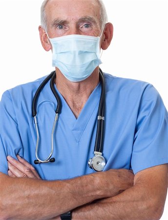 Strong male nurse or surgeon dressed in blue scrubs and face mask with stethoscope round his neck. He is looking at camera with arms folded. Isolated on white. Photographie de stock - Aubaine LD & Abonnement, Code: 400-04808877