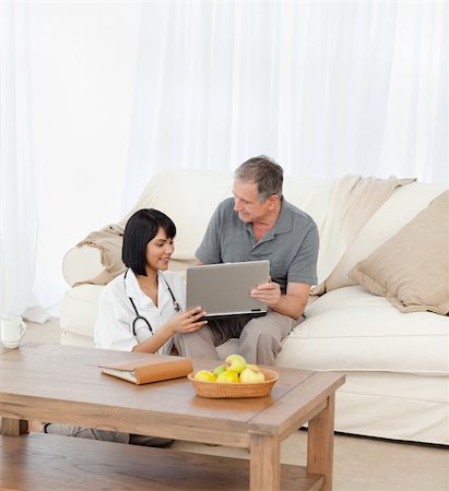 simsearch:400-04809124,k - Mature man with his nurse looking at the laptop at home Stockbilder - Microstock & Abonnement, Bildnummer: 400-04809123