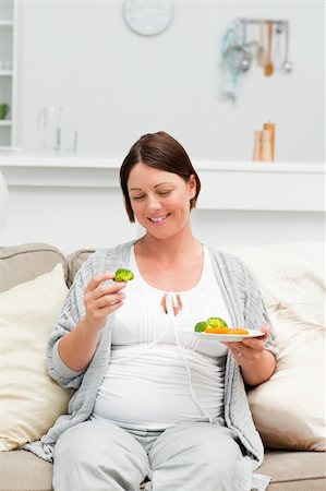 simsearch:400-04767824,k - Pregnant woman eating vegetables on her sofa Foto de stock - Royalty-Free Super Valor e Assinatura, Número: 400-04800916